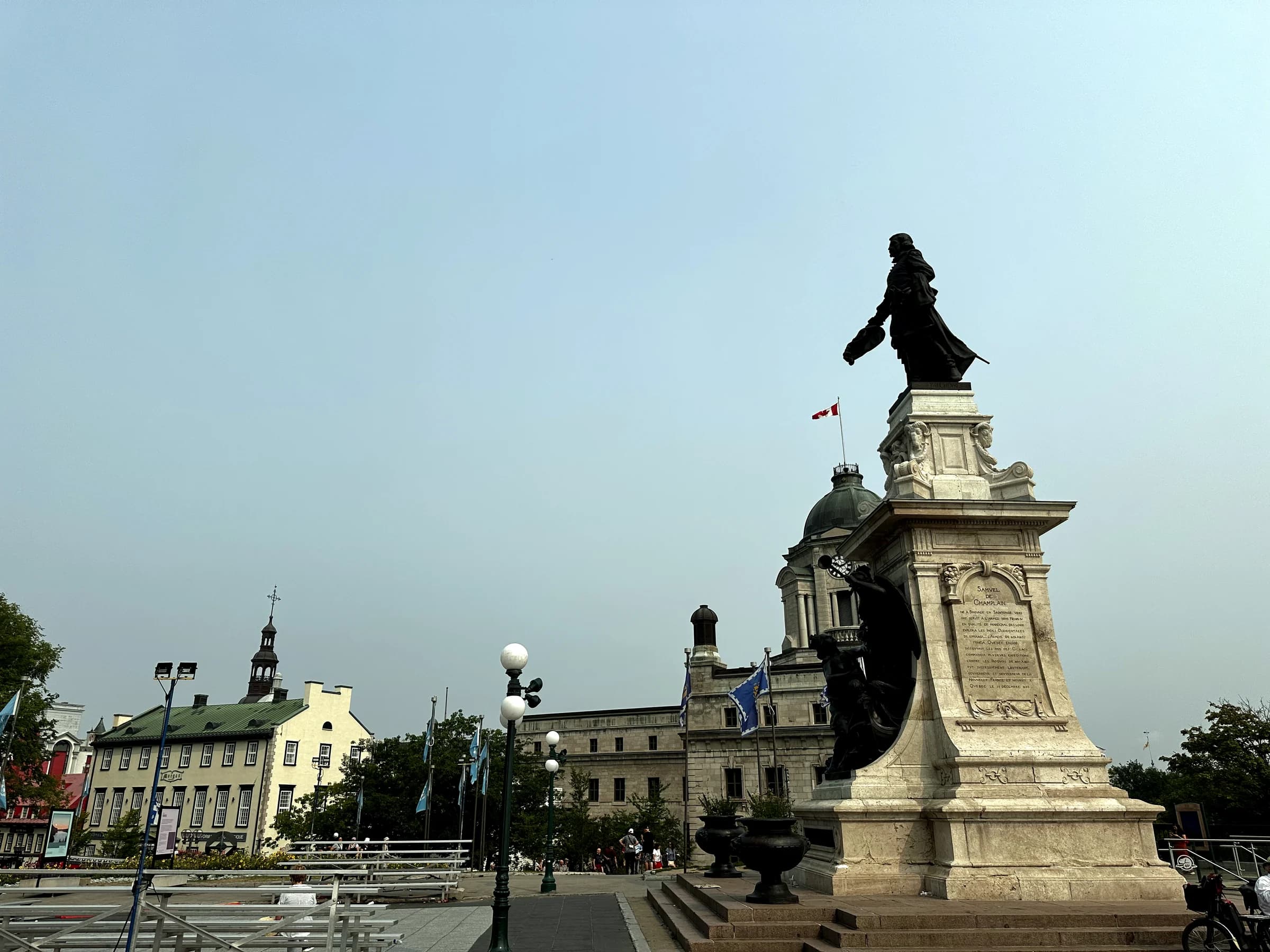 A monument and historic civic buildings beneath an overcast sky in Quebec City