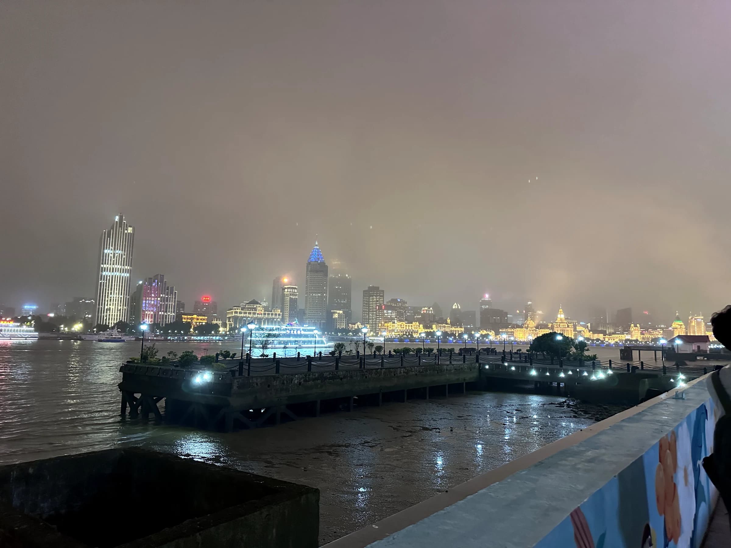 Shanghai skyline glowing through humid night air across the Huangpu River
